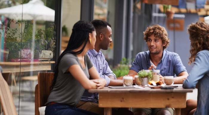 Four people dine outdoors.