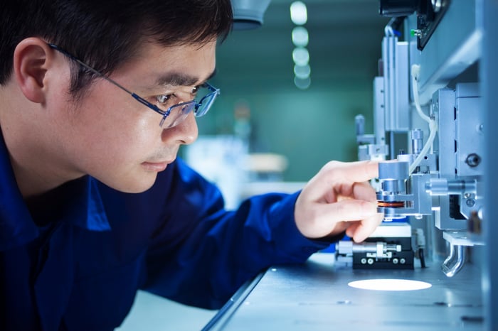 A quality control inspector closely looking at semiconductor machinery.