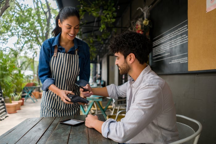 A person making a contactless payment at a restaurant.