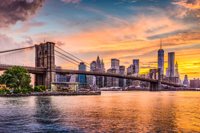 The Brooklyn Bridge with the Manhattan skyline at sunset in the background.