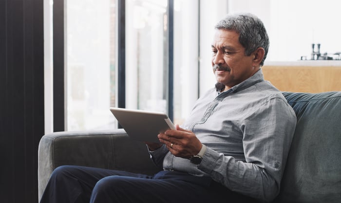 A person on a couch holding a tablet.