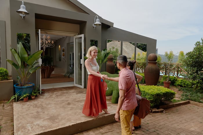 Two people shaking hands in front of a house.