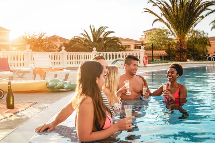 Five people drinking champagne in a pool.