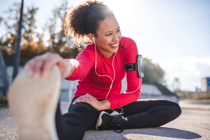 A person in fitness clothing stretching hand to pull shoe.