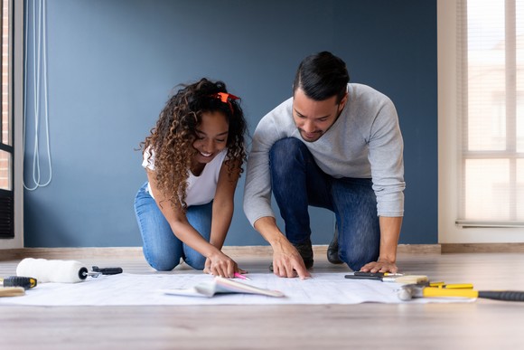 Two people bending over floor plans.