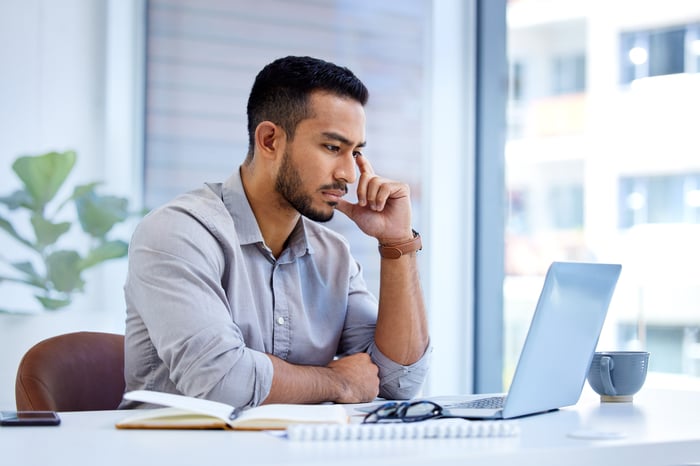 A person with a serious expression at a laptop.