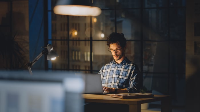 A person at a laptop in a dark room.