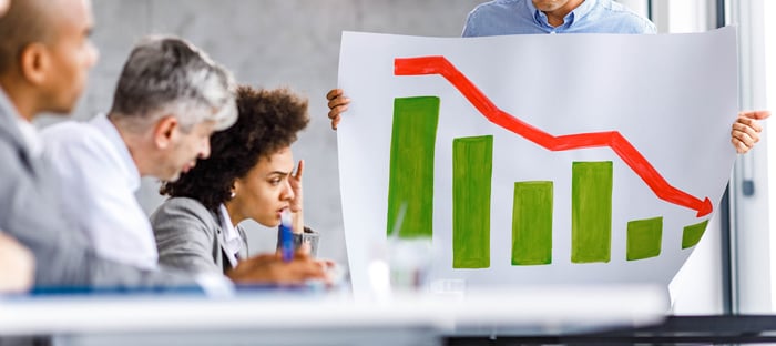 People at a conference table staring at a graph with a steep downward trend.