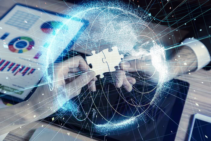 Two hands connect two puzzle pieces with tech graphs and animations around it.  