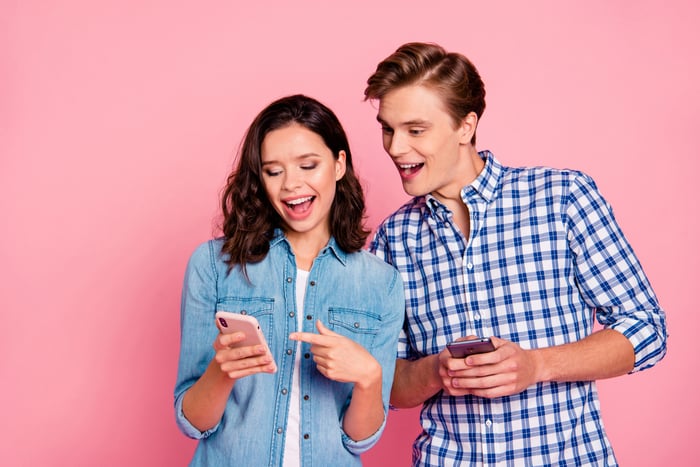 Two people check their smartphones together.