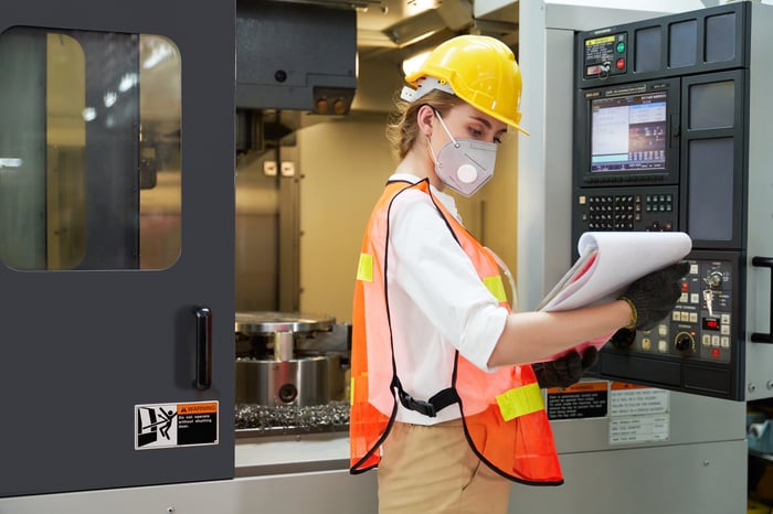 Factory worker checking on a machine.