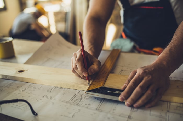 Contractor measuring a wood plank.