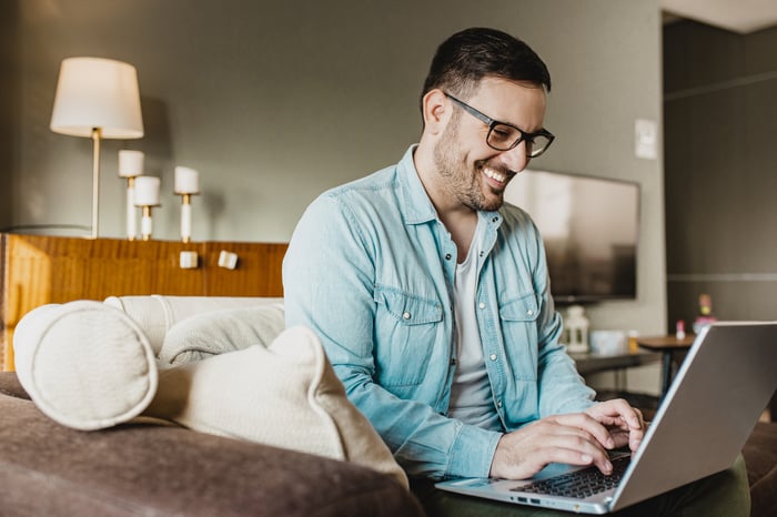 A smiling person typing on a laptop.