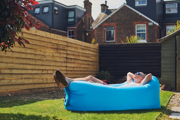 Person relaxing on a lounger in their backyard.