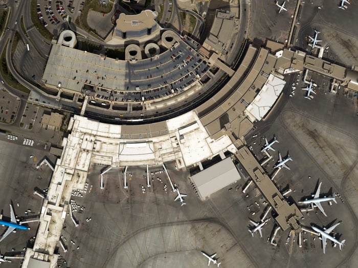 An overhead view of an airport terminal with airplanes parked at some of the gates.