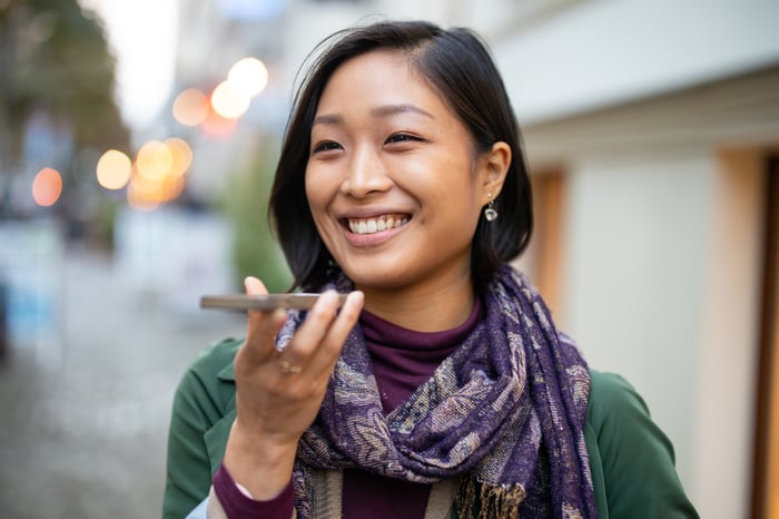 A person using the speakerphone function on their phone while walking down a city street.