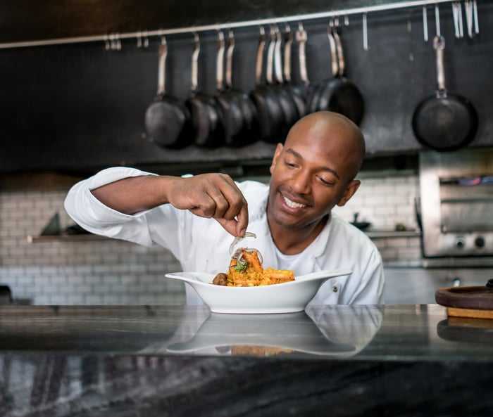 A chef putting garnish on a dish.