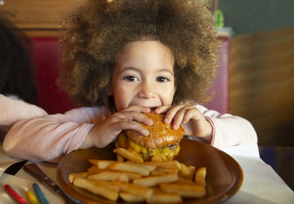 A child eating a hamburger and fries.