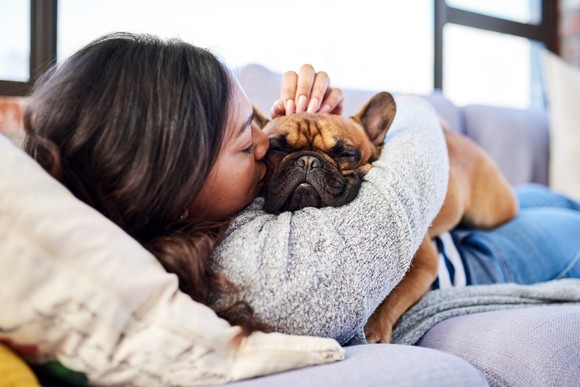 Woman on a couch cuddling a dog.
