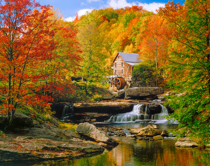 Cabin with river and waterfall in mountains.