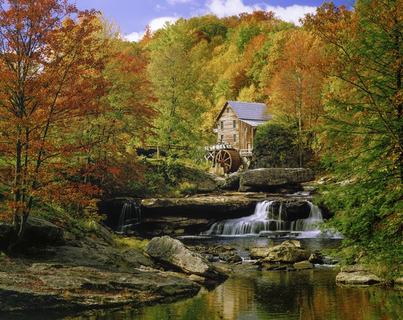 Cabin with river and waterfall in mountains.