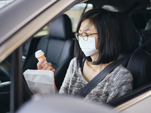 A person picks up a prescription at a drive-thru pharmacy.