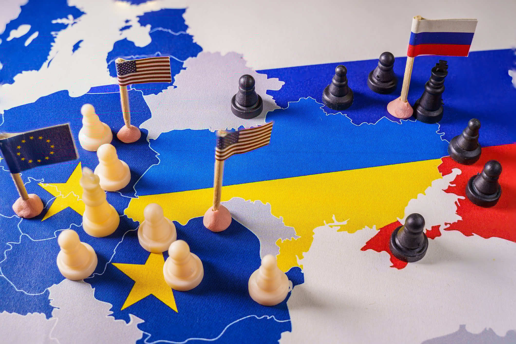 Chess pieces and Russian US and EU flags surround a map of Ukraine.