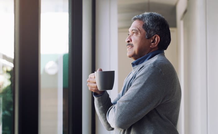 Person holding a mug and looking out a window.