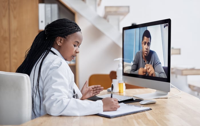 A doctor conducting a telehealth visit with a patient on a computer. 