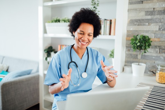 A doctor conducts a telemedicine visit using a laptop in a medical office.