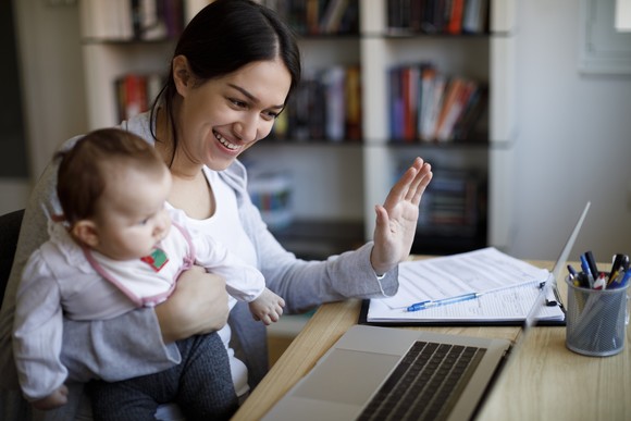 An adult and a baby look at a laptop during a telemedicine visit.