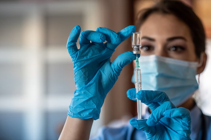 A healthcare worker draws up a dose of vaccine in a syringe. 