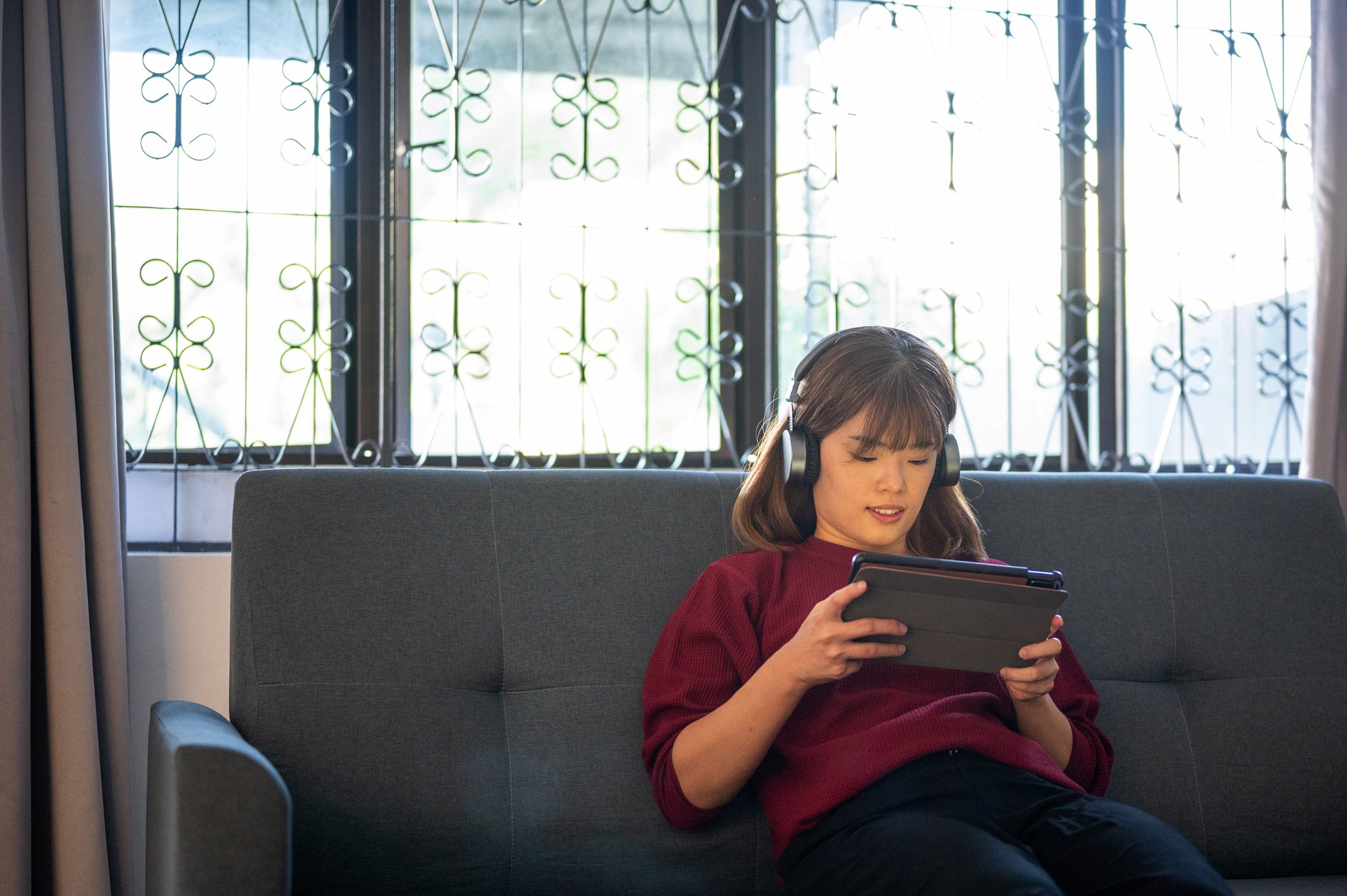 A young adult wearing headphones will looking at a tablet