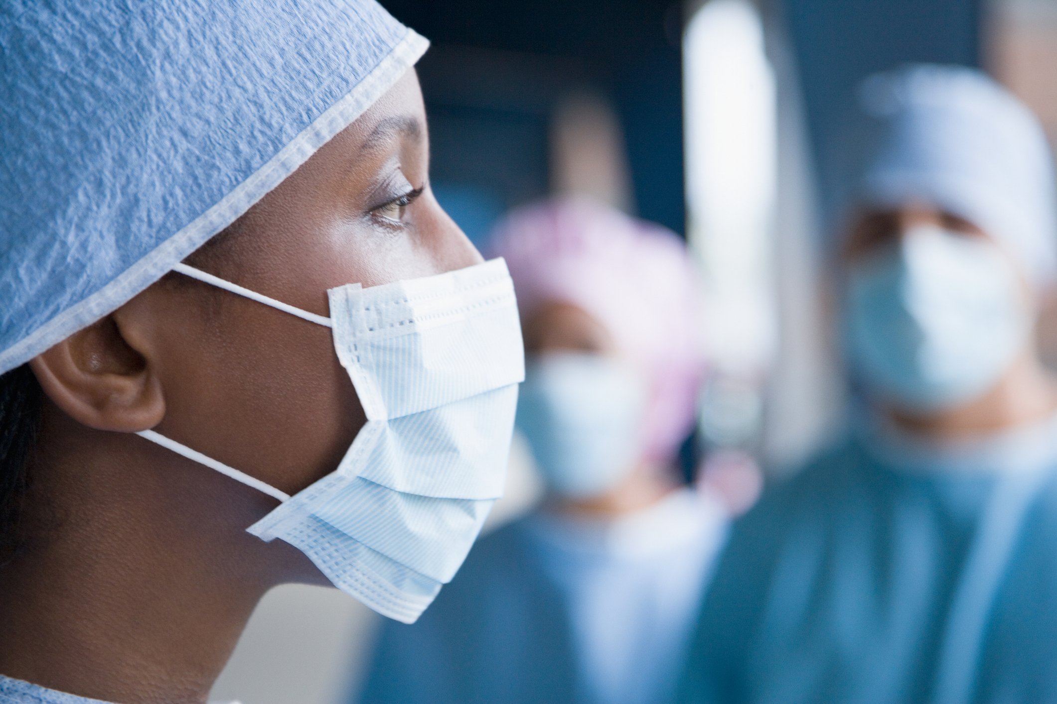 20_08_04 A person in a surgical mask and attire with similarly clad people behind them _GettyImages-87652267