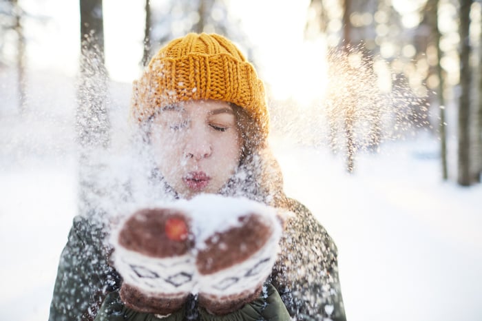 Person blowing snow out of mittens.