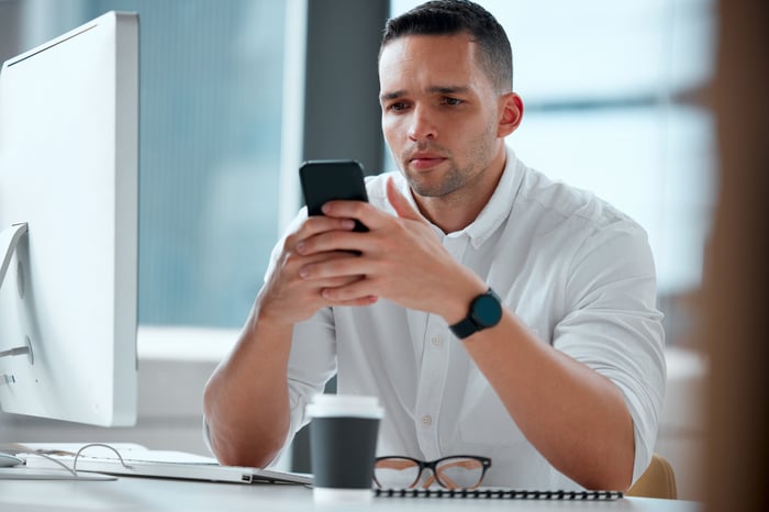 A person with a serious expression holding a phone.