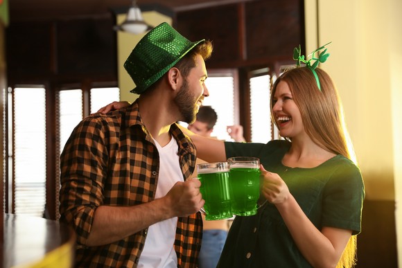Two smiling people holding mugs with a green drink.