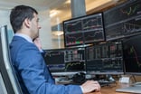 Businessman_studying_stock_charts_on_multiple_computer_screens