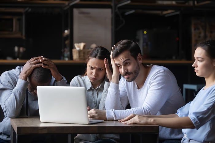 A group of disappointed people sitting around a computer.