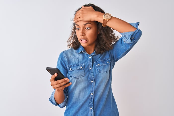 A person with a shocked expression looking at a cellphone.