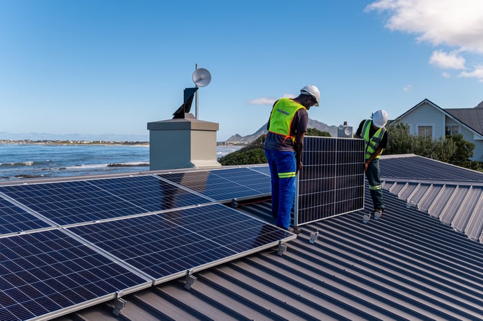 solar panel installers on a coastal residential roof.