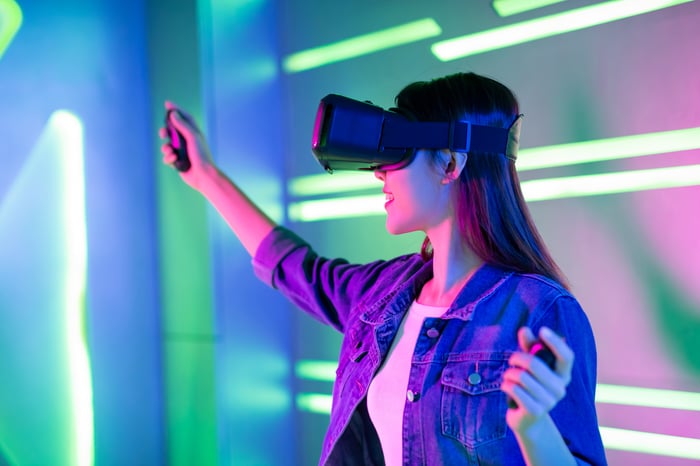 A smiling person playing a game with a virtual reality headset on.