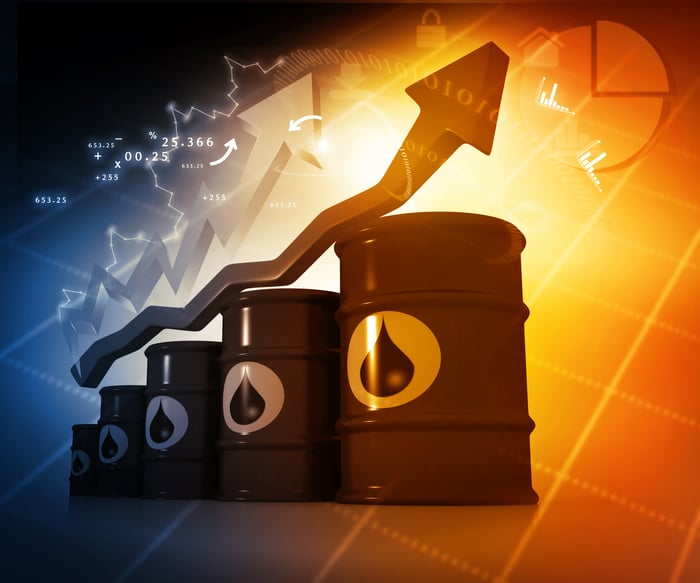 Stock market arrow rising above a stack of oil barrels.
