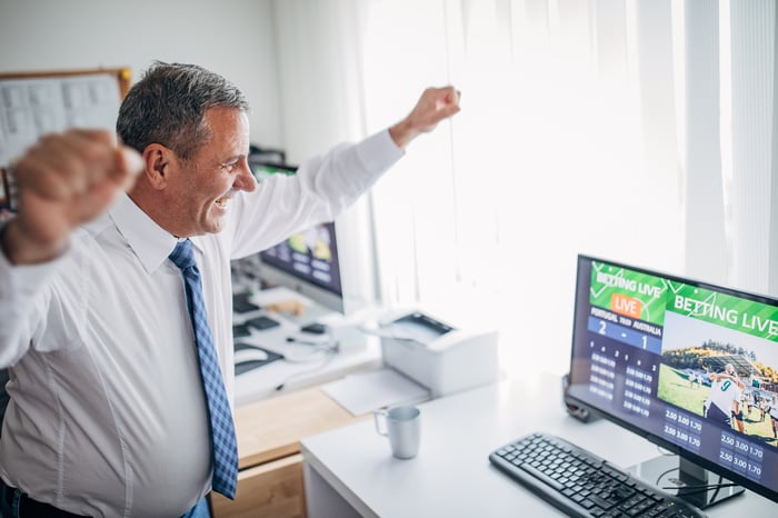 A person looking at a computer screen and cheering.