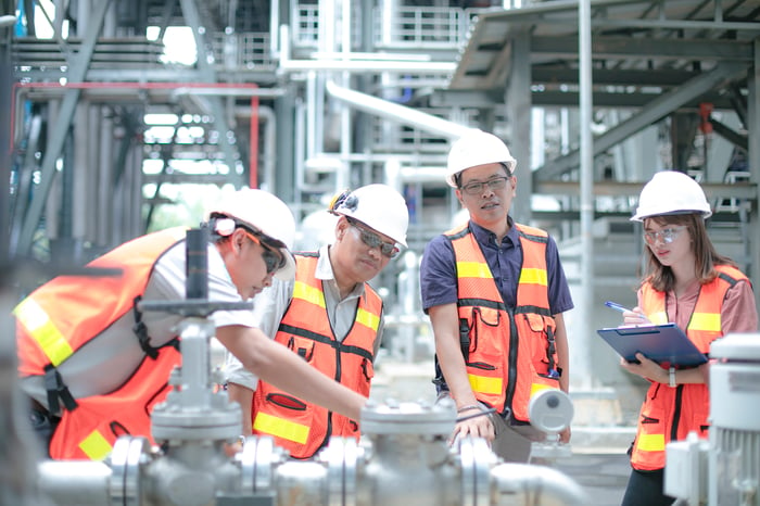 People in protective gear in an energy processing facility.