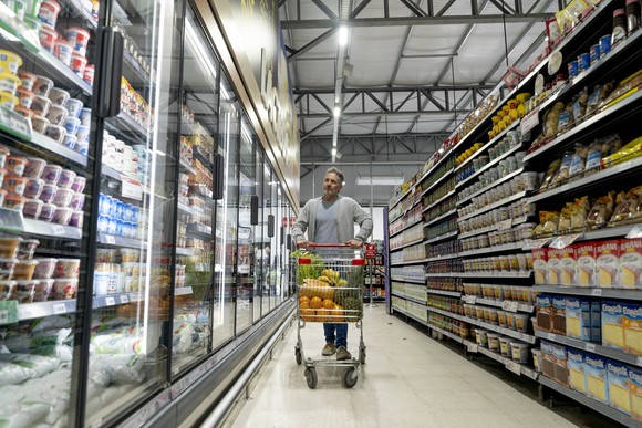 Person pushing a shopping cart on grocery aisle.