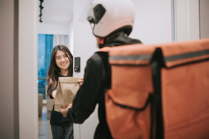 Person at an open door accepting a food delivery.