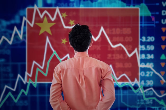 A person examines a stock chart superimposed on a Chinese flag.