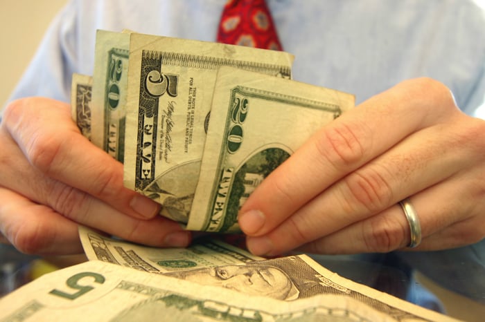 A businessperson counting an assortment of cash bills. 