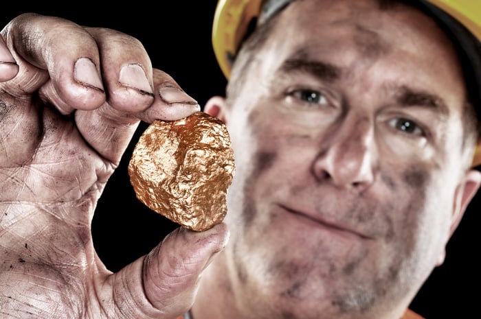 Miner holding up a gold nugget.